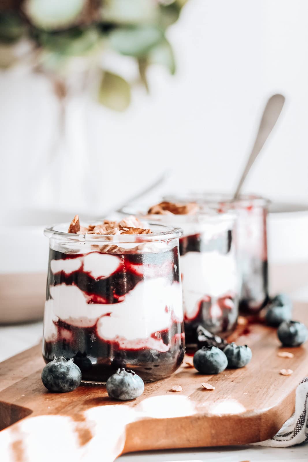 Three blueberry parfaits on a serving board