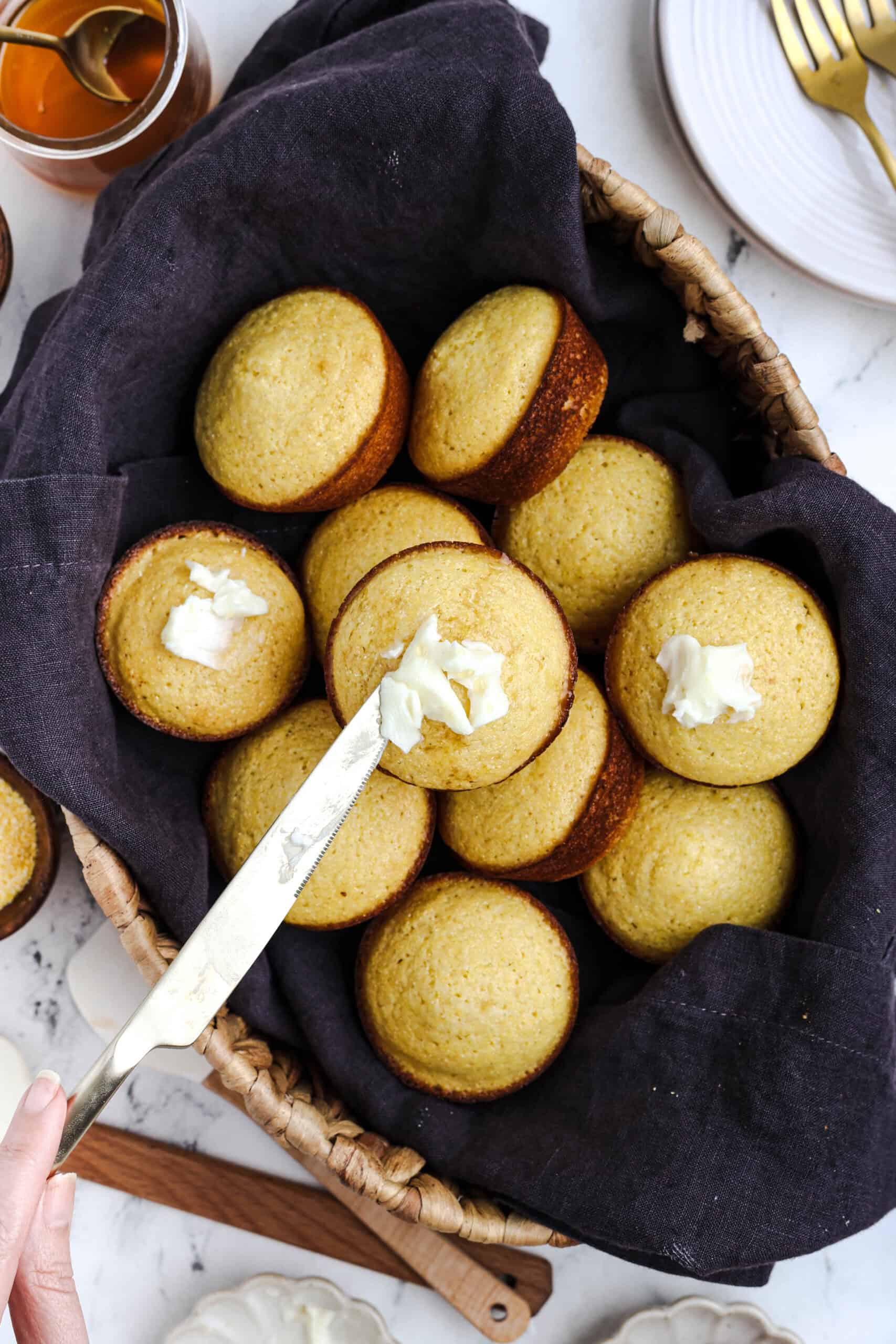 Honey cornbread muffins in a basket with butter.