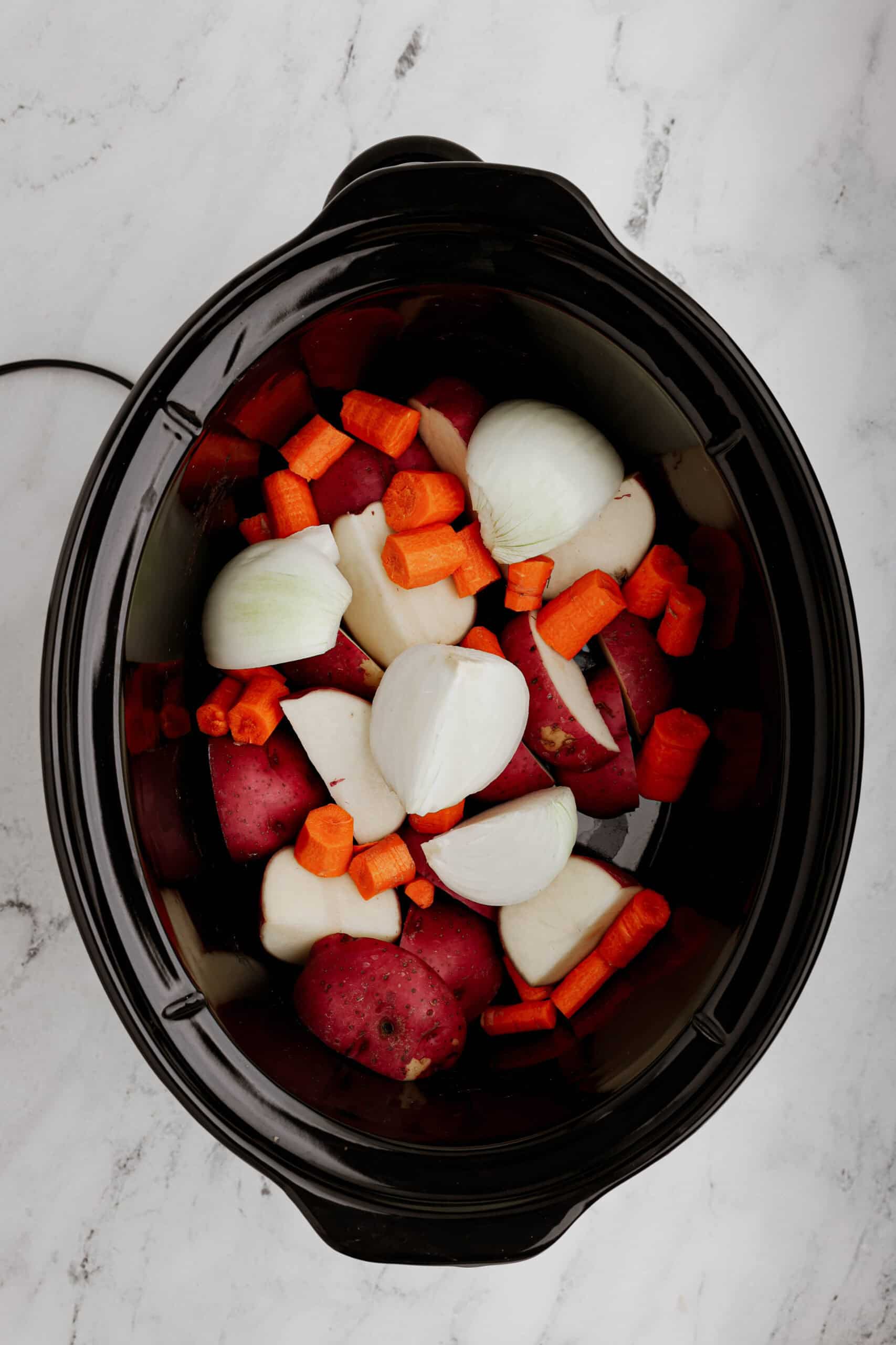 Add vegetables to a slow cooker.