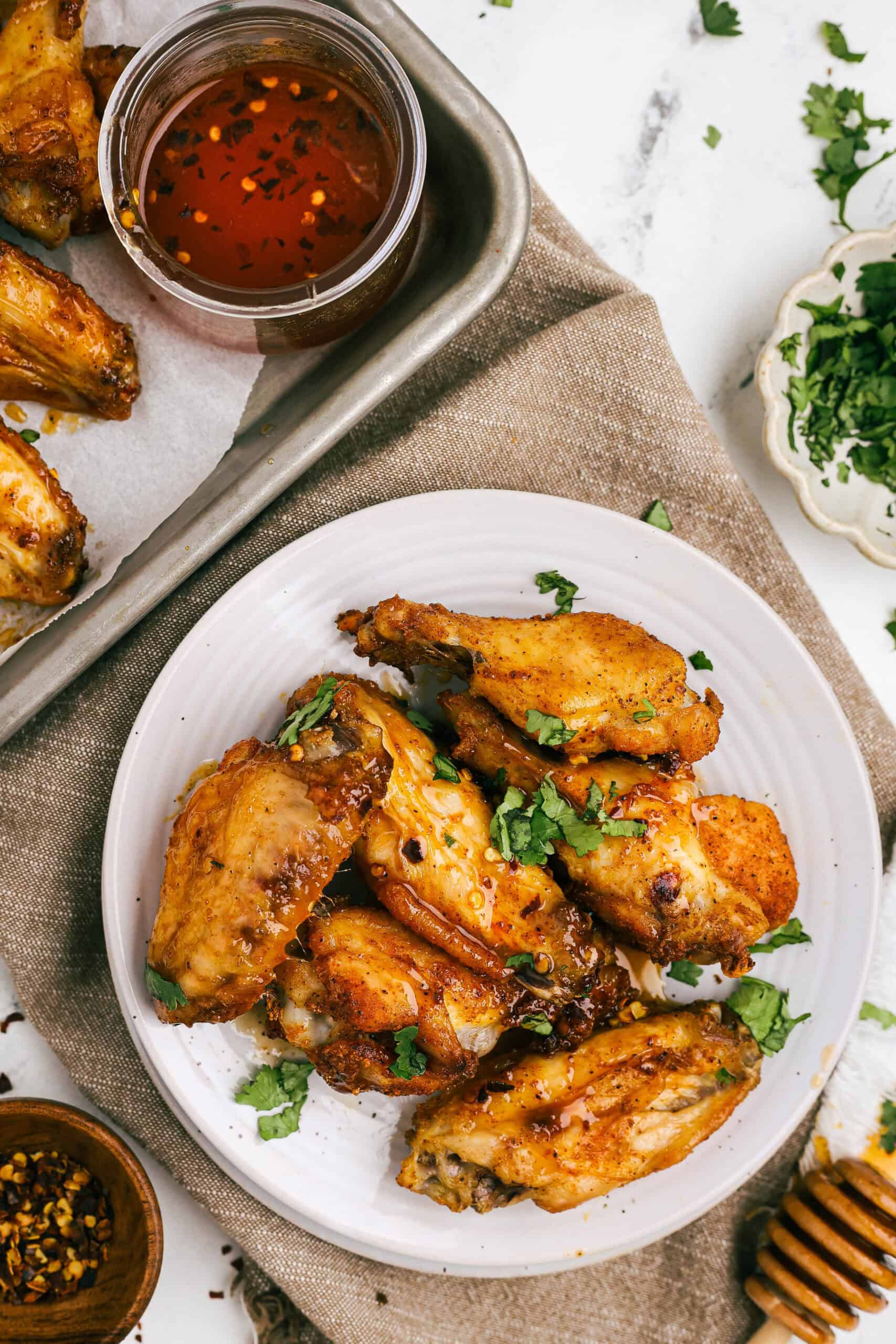 Plate of crispy hot honey chicken wings drizzled with spicy honey sauce and sprinkled with fresh cilantro.