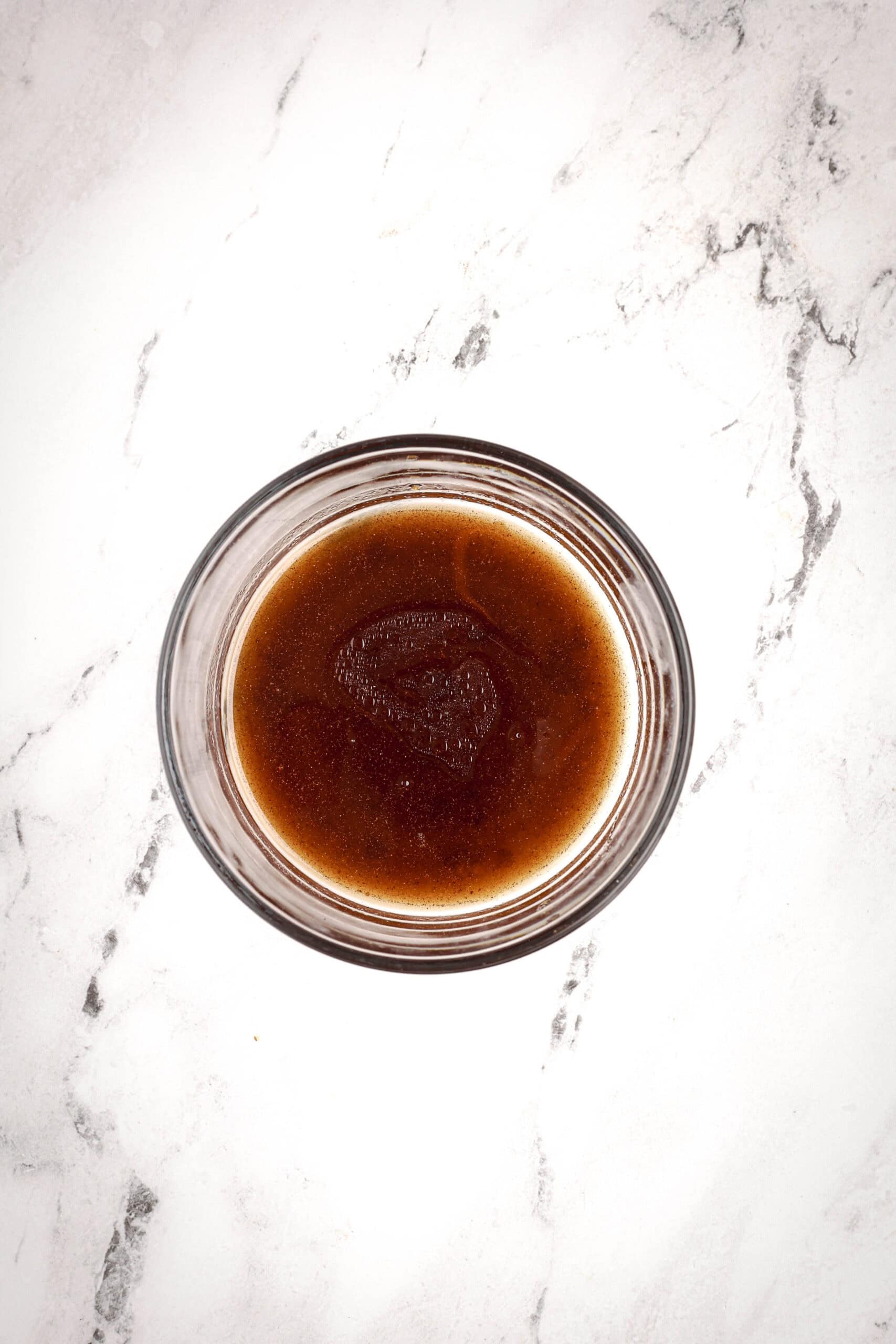 A close-up of the maple glaze mixture in a glass bowl, showing its dark glossy color and smooth texture.