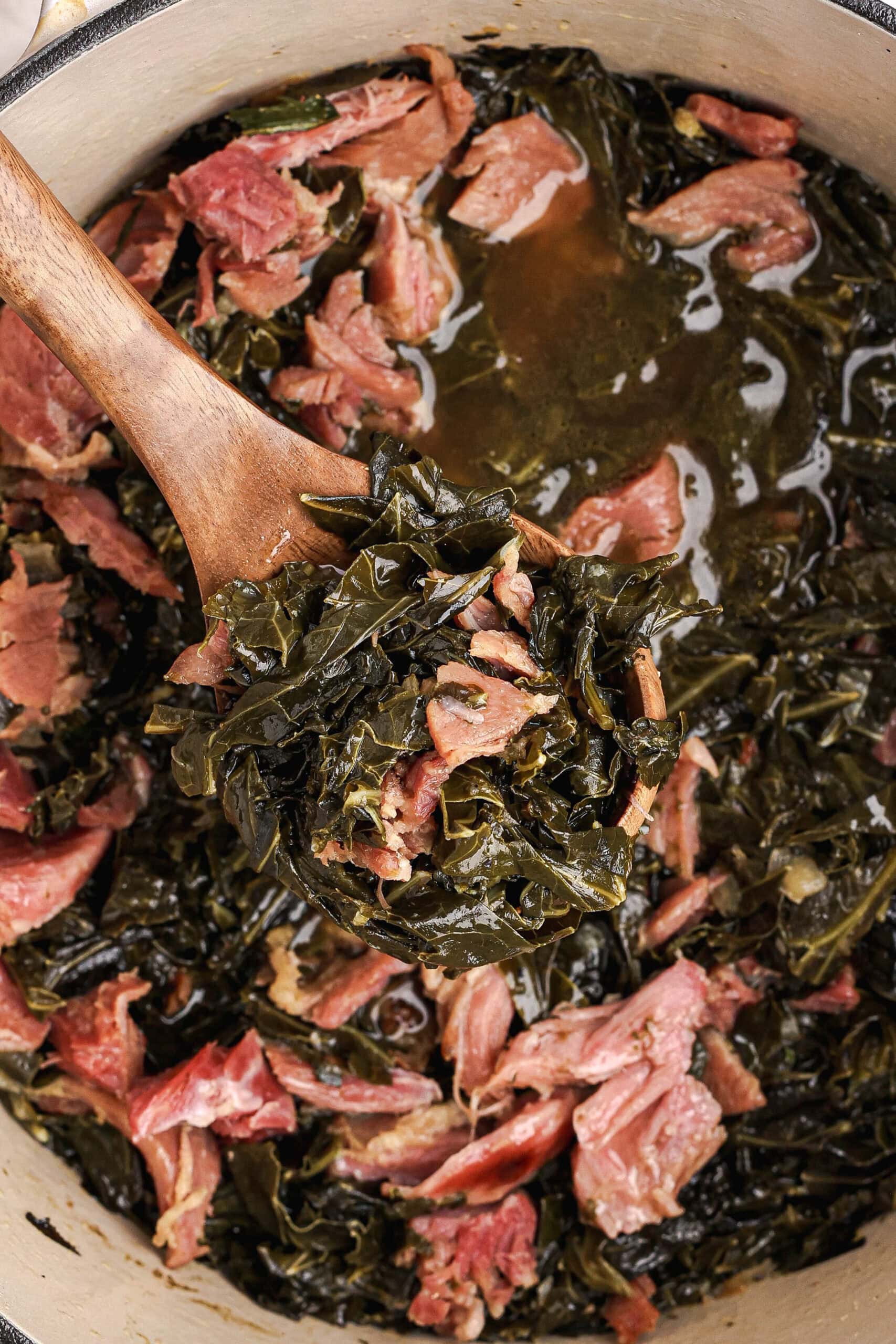 Close-up of tender collard greens and shredded ham in rich broth.