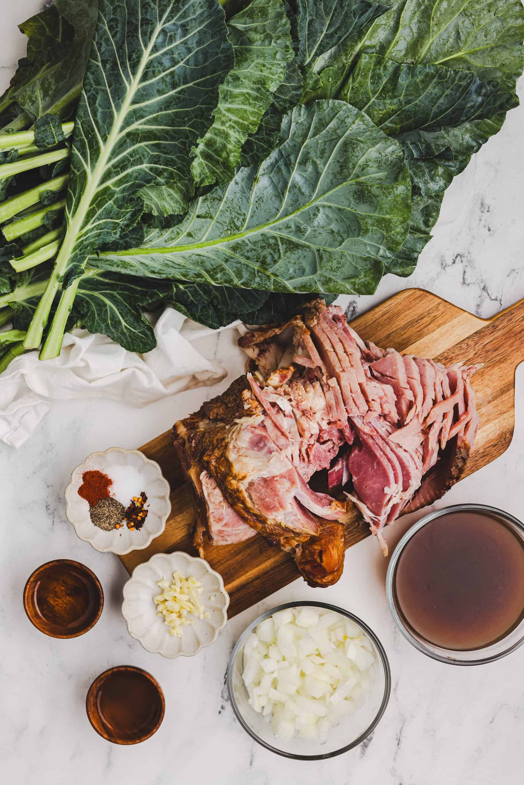 Ingredients for Southern collard greens including ham bone, chopped onion, broth, and fresh greens.