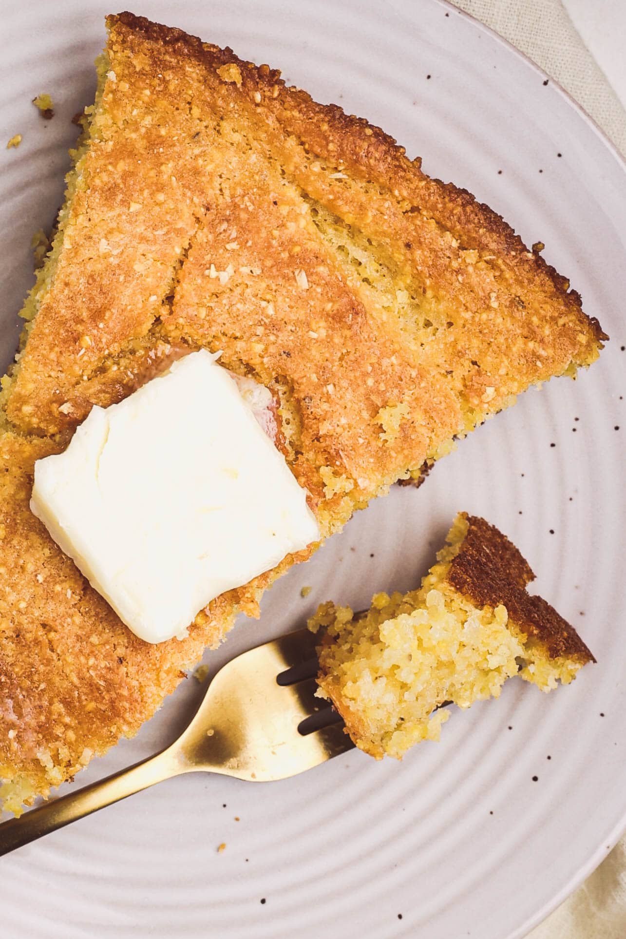 Close-up of buttery cornbread slice showing a tender crumb and crisp edges.