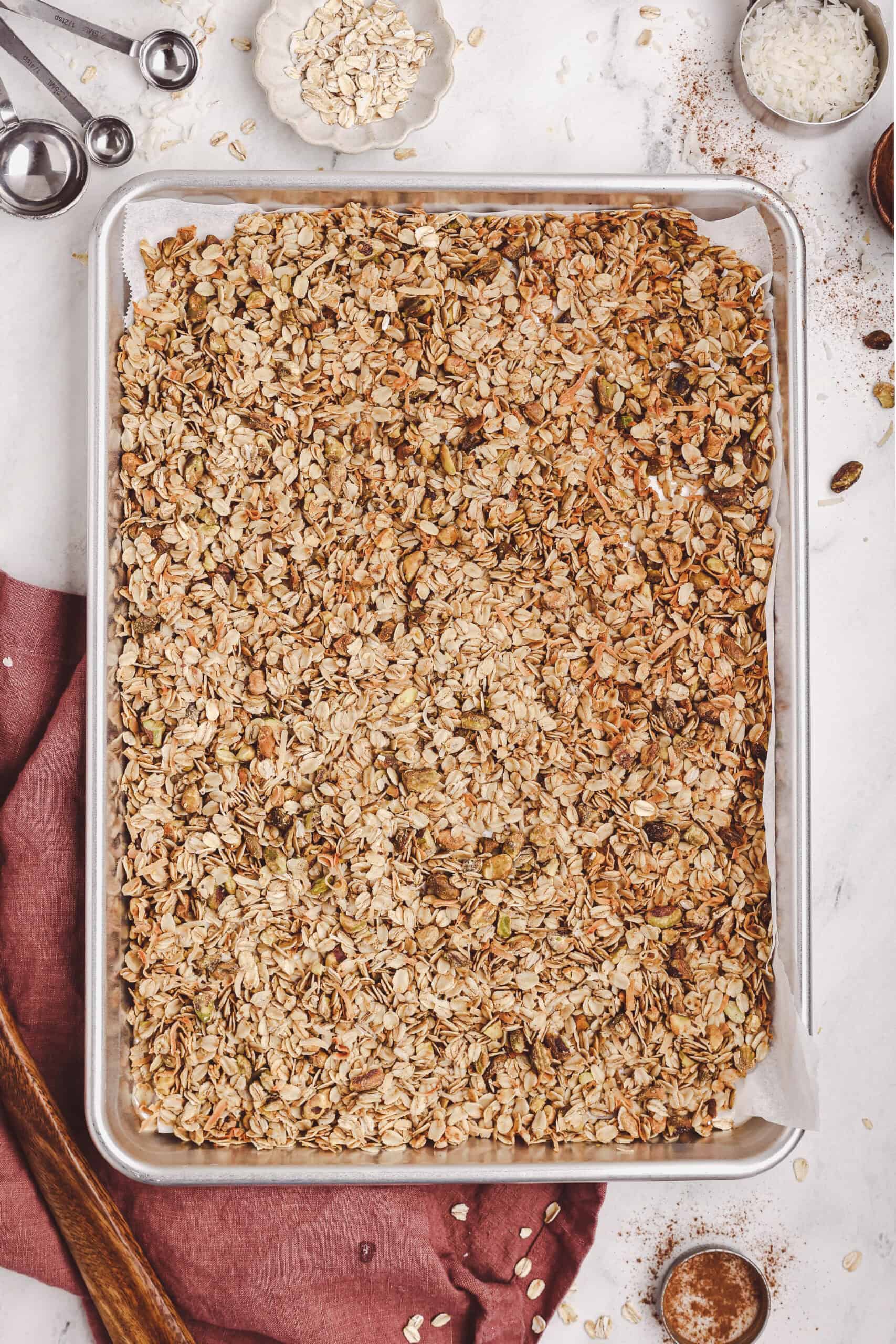 Homemade granola spread on a parchment-lined baking sheet.
