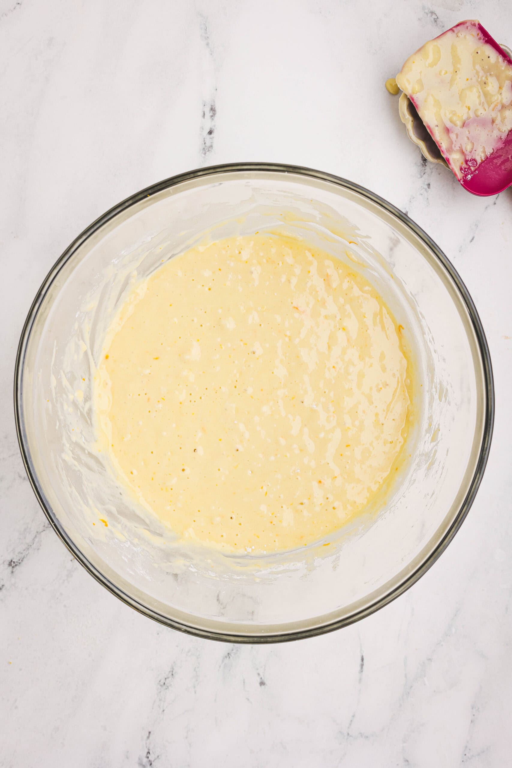 Thick orange loaf batter mixed in a bowl with visible zest and smooth texture.