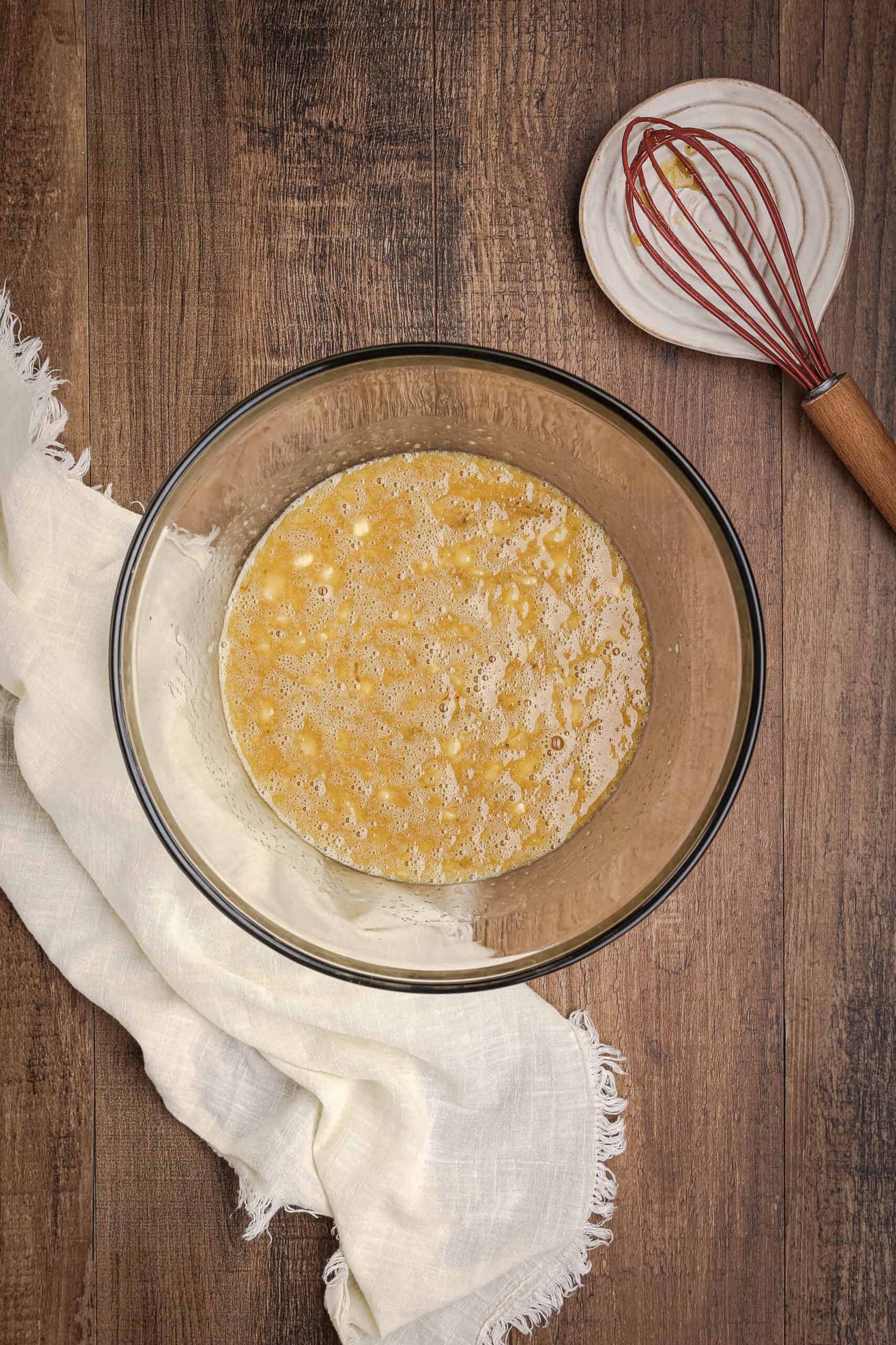Mashed bananas mixed with eggs and oil in a glass bowl for carrot cake banana bread batter
