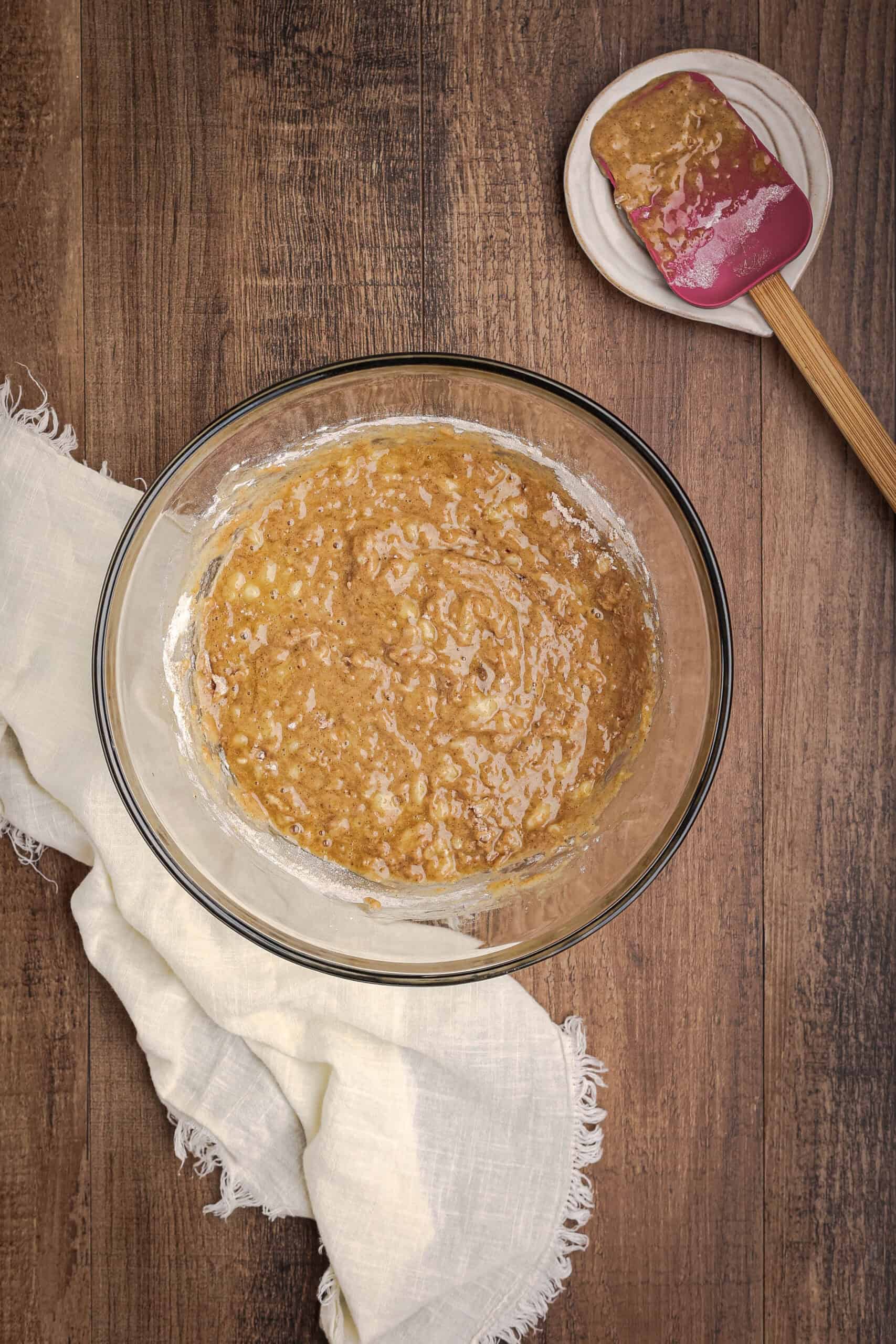 Banana bread batter partially mixed with flour being folded into wet ingredients