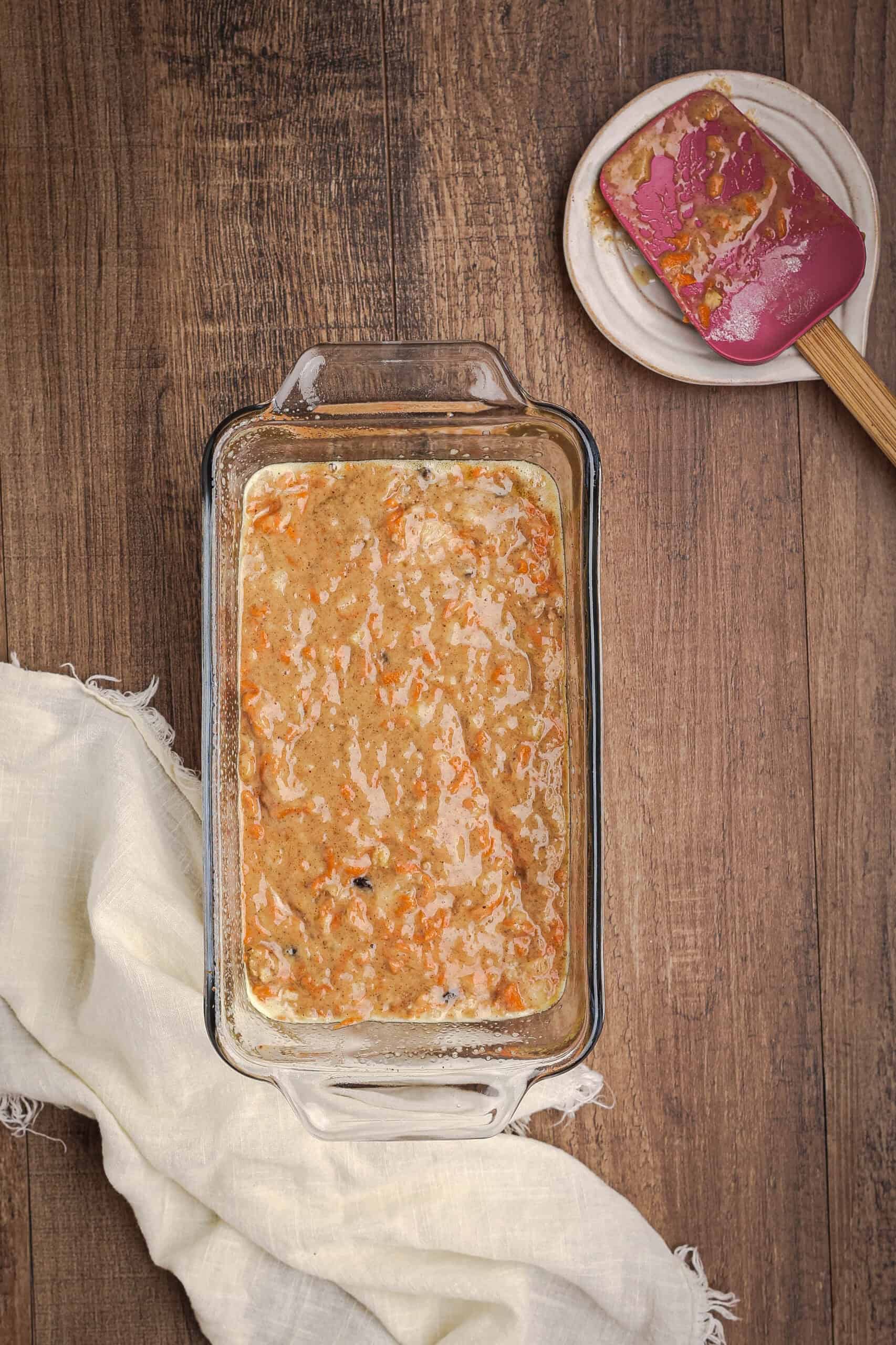Carrot cake banana bread batter poured into a glass loaf pan before baking