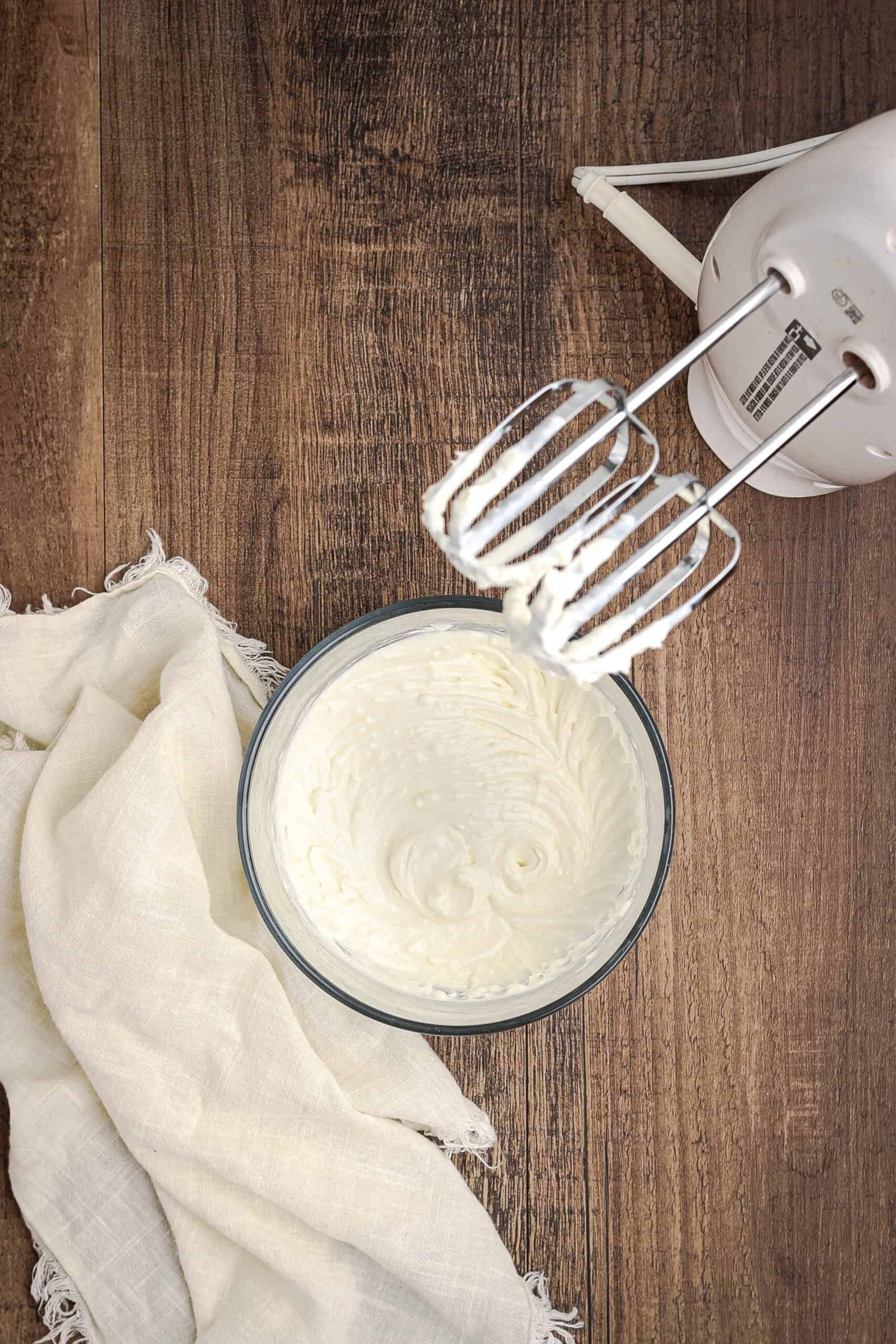 Cream cheese icing being whipped with electric hand mixer