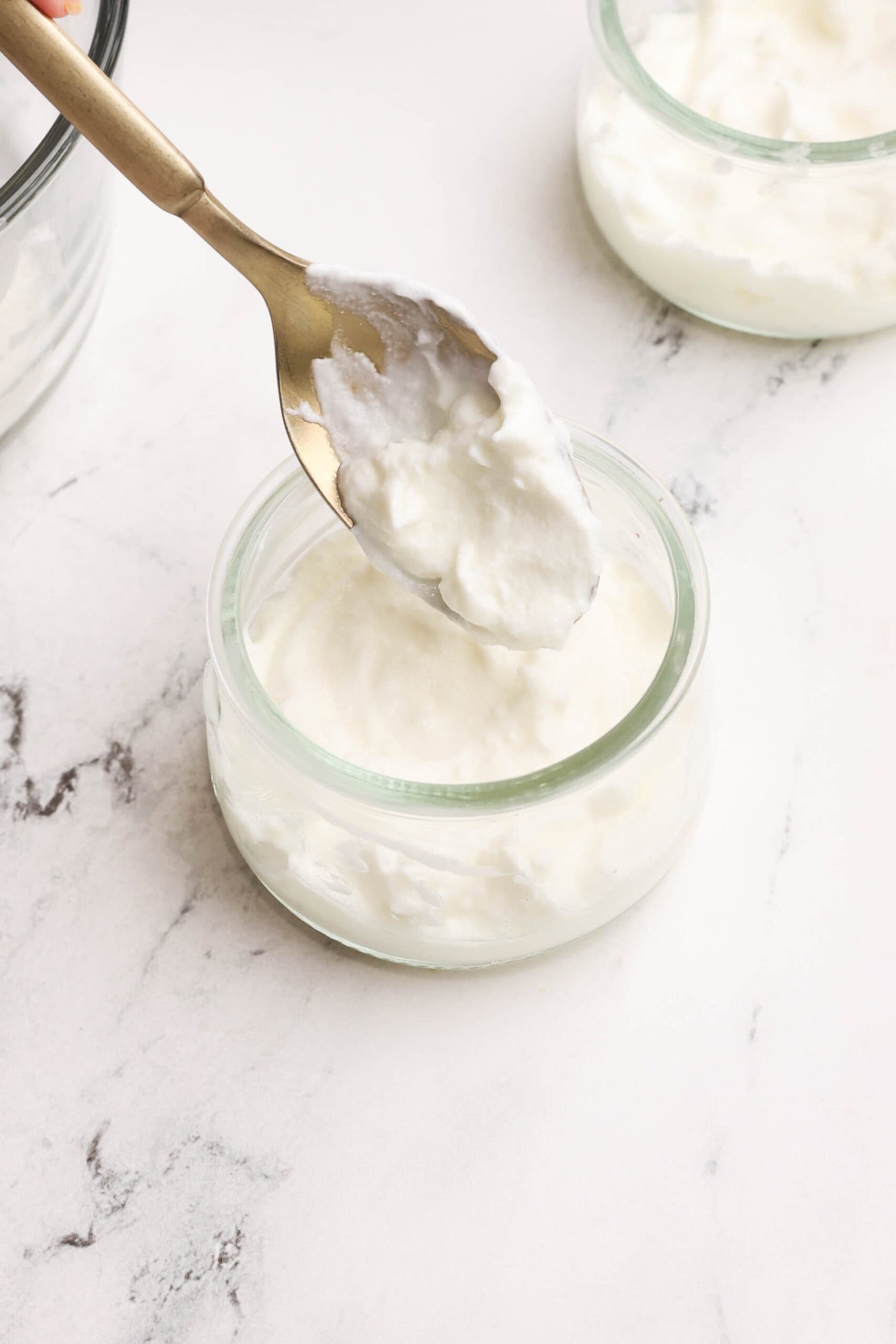 Layering yogurt into a glass jar with a spoon.