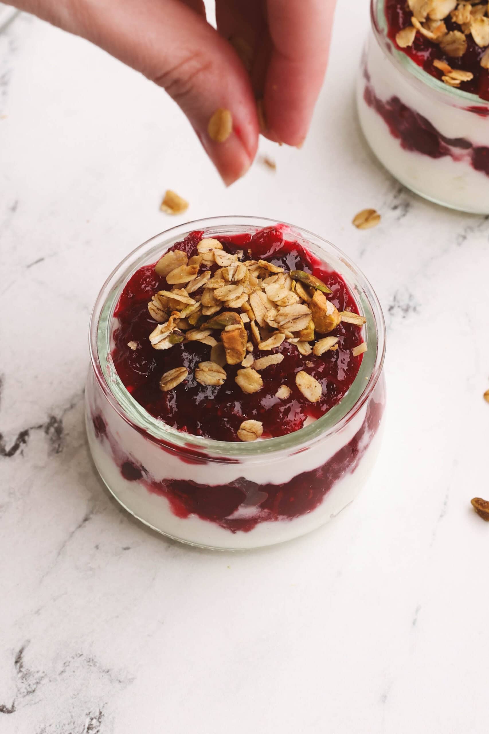 Topping the parfaits with a sprinkle of granola.