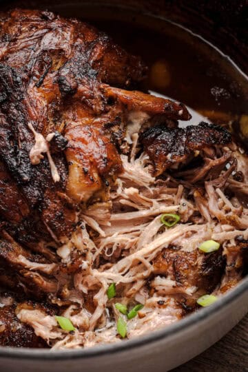 Close-up of slow-roasted mojo pork shoulder pulling apart into tender strands inside a Dutch oven.