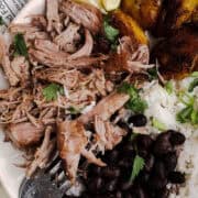 Close-up of authentic mojo pork served with Cuban black beans, white rice, and caramelized sweet plantains.