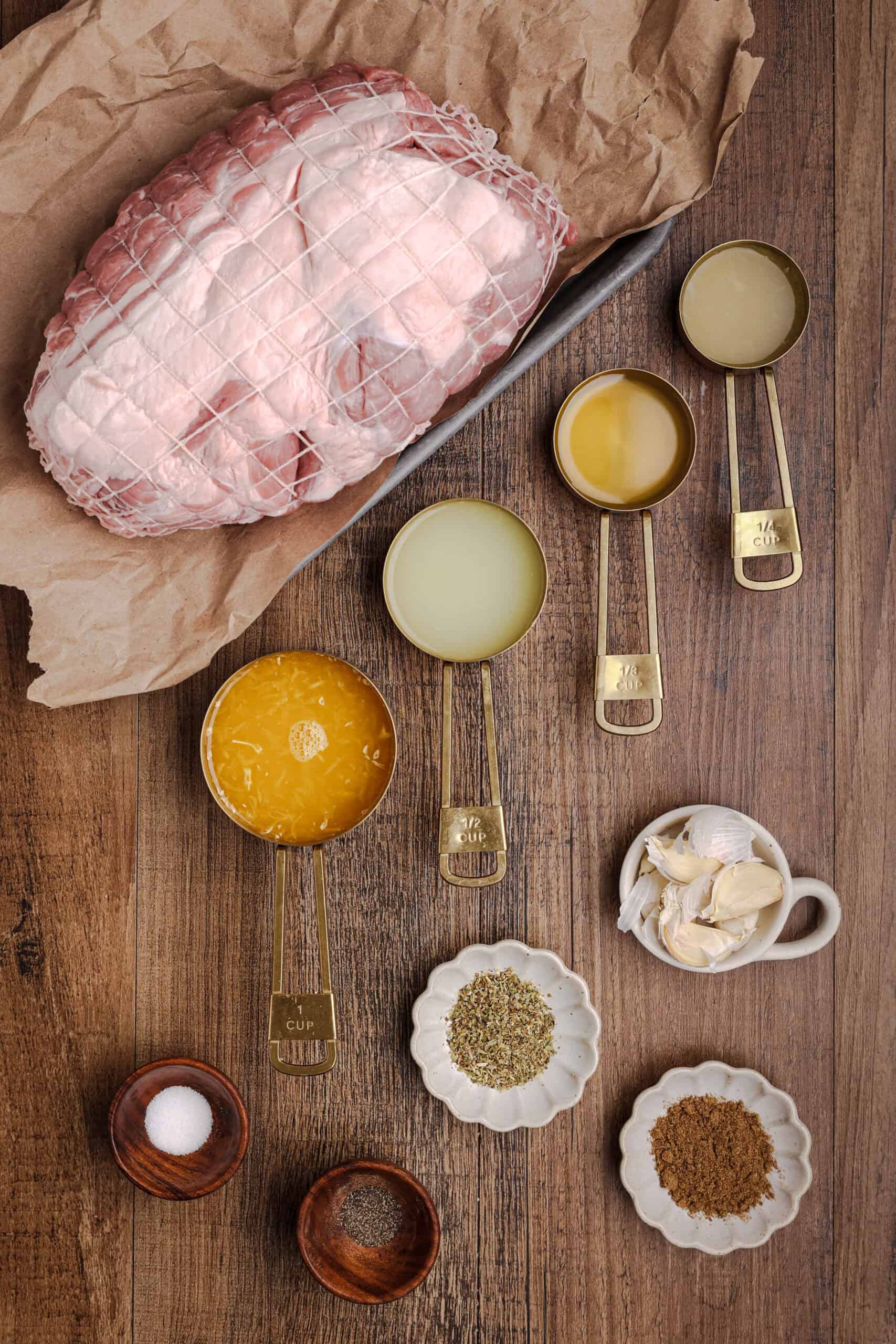 Ingredients for authentic Cuban mojo pork roast including pork shoulder, orange juice, lime juice, lemon juice, garlic, oregano, cumin, salt, and pepper.