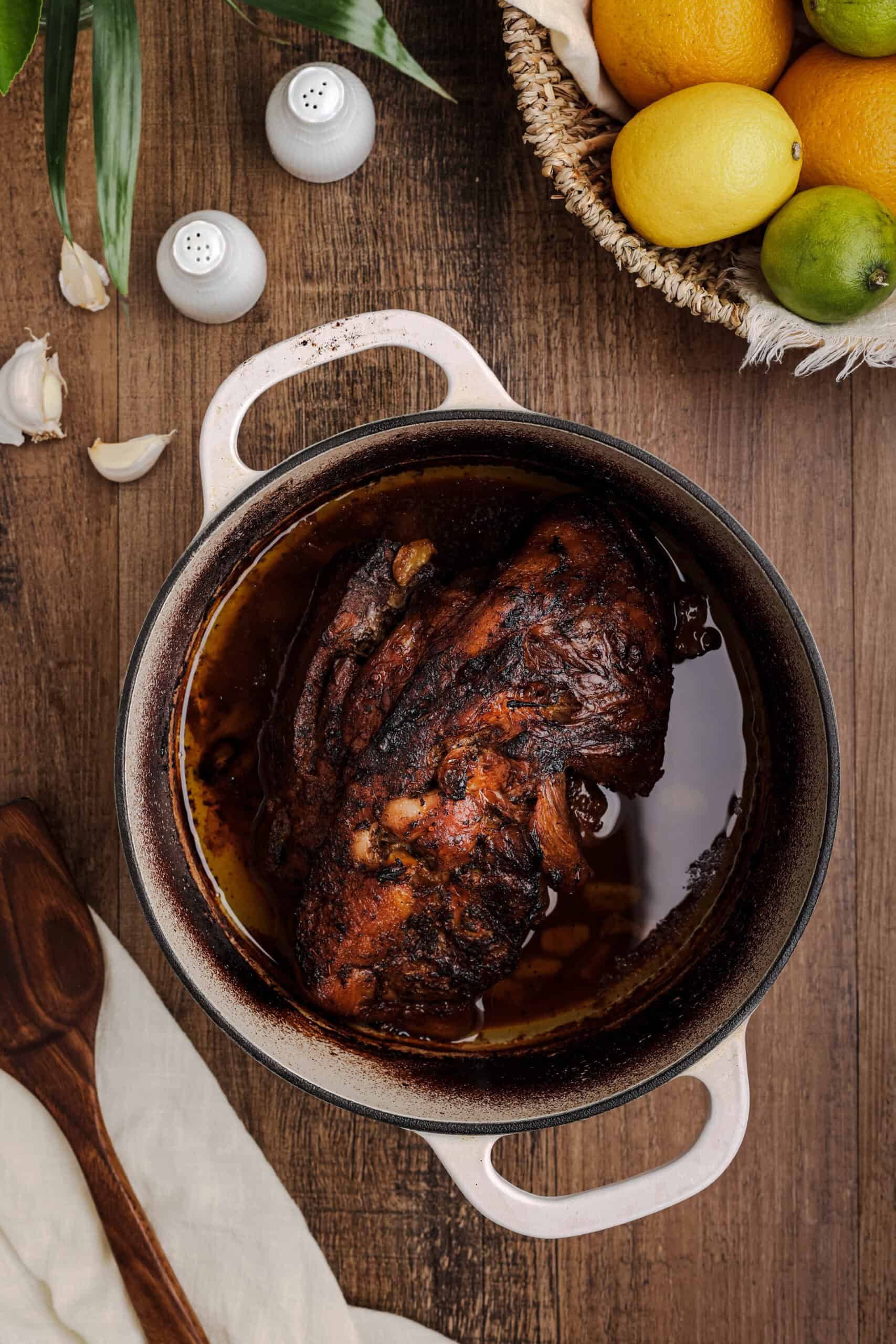Authentic Cuban mojo pork roast cooking in a Dutch oven surrounded by citrus marinade and garlic.