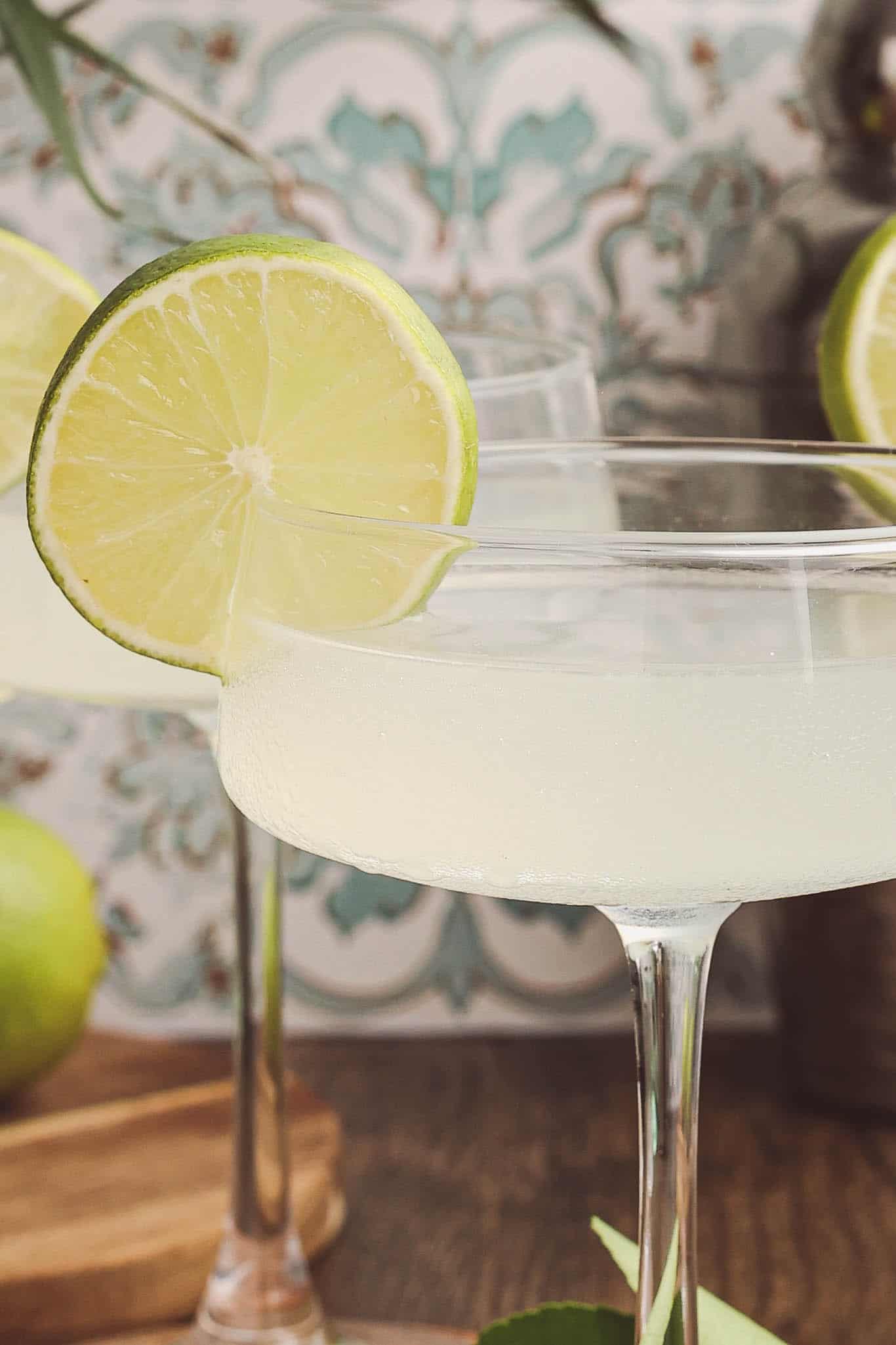 Close-up of a classic daiquiri cocktail with a lime wheel garnish in a chilled coupe glass.