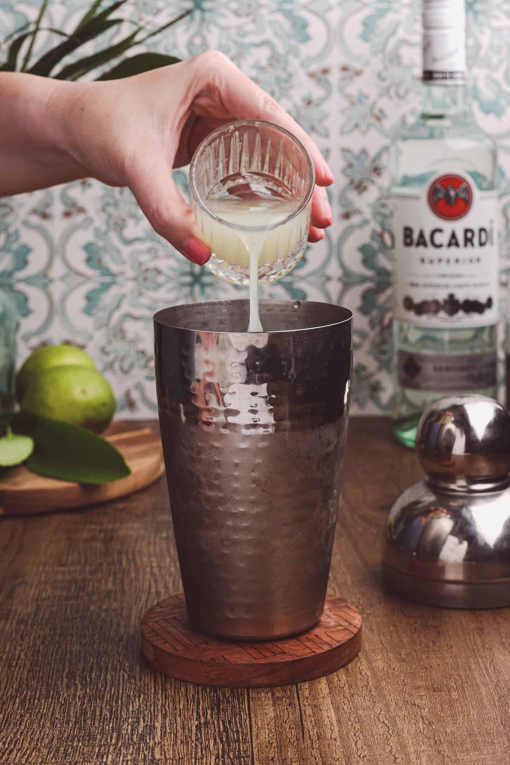 Adding fresh lime juice to a cocktail shaker while making a classic daiquiri.